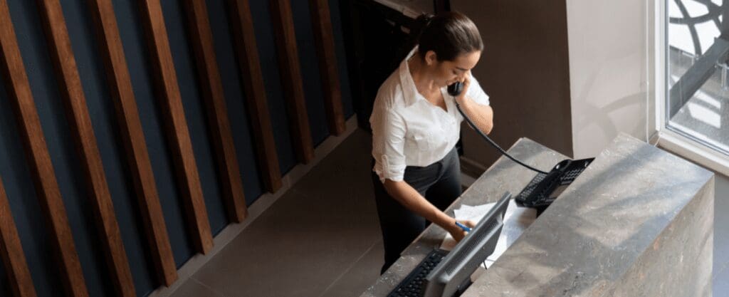A woman on the phone at the front desk in a hotel lobby.