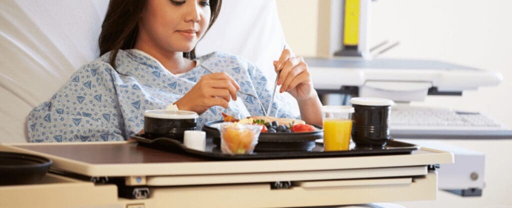 A happy patient eating food in their hospital bed.