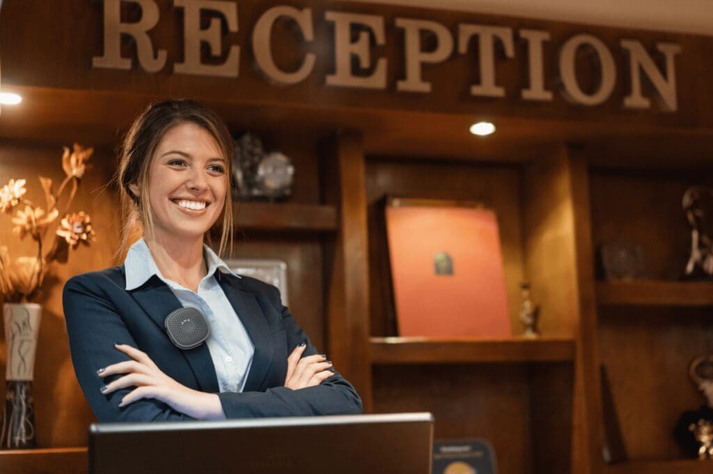 Woman with Relay device standing in front of hotel reception | Blog cover for Hospitality Communication Best Practices for Hotel Teams