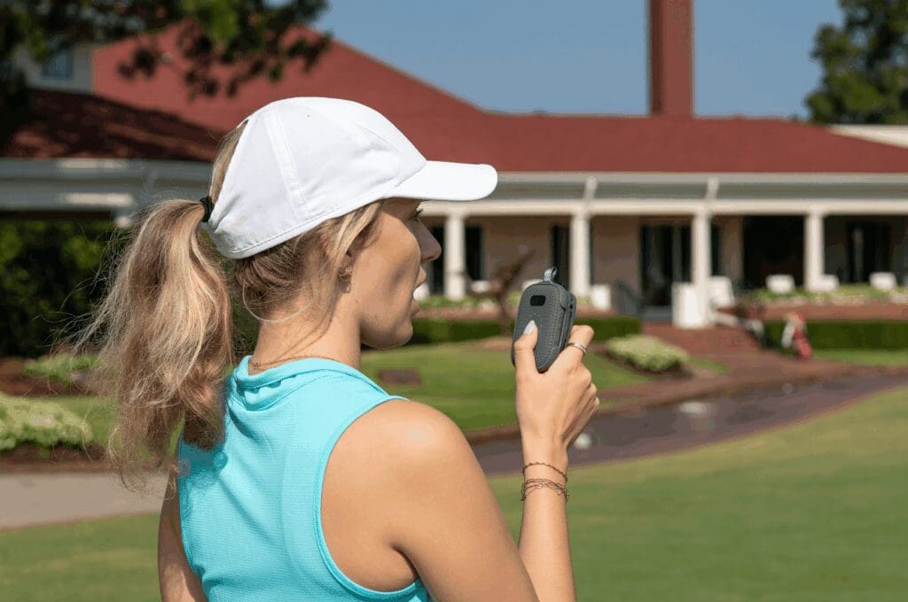 Woman wearing teal shirt using RelayX as walkie talkie on the golf course