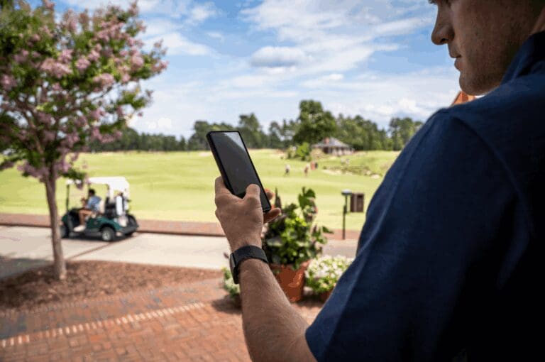 Man holding communication technology, cell phone, while on a golf course
