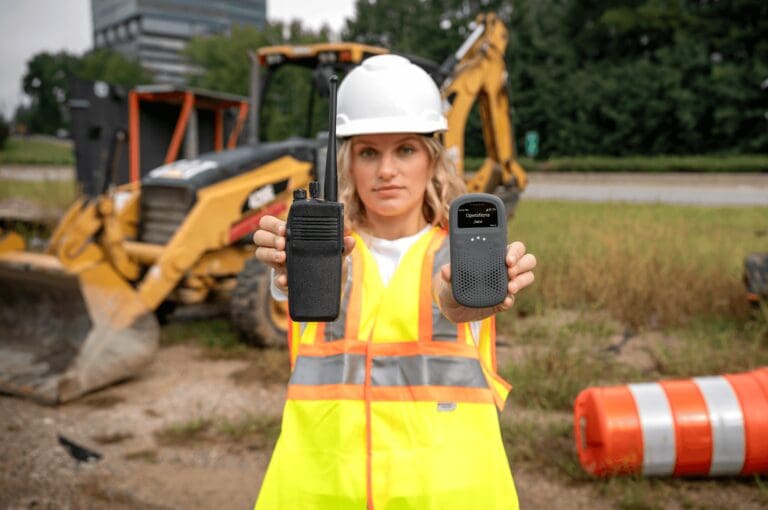 Woman in construction site holding Traditional Radio and RelayX