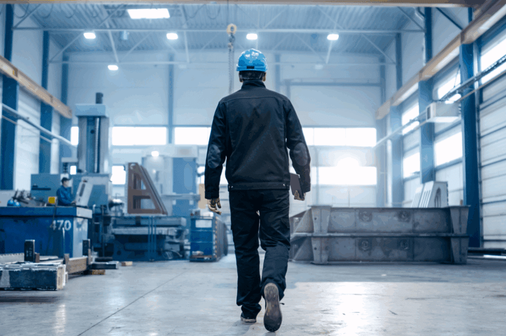 Industrial worker walking through facility with device in hand showing the impact of artificial intelligence on modern manufacturing