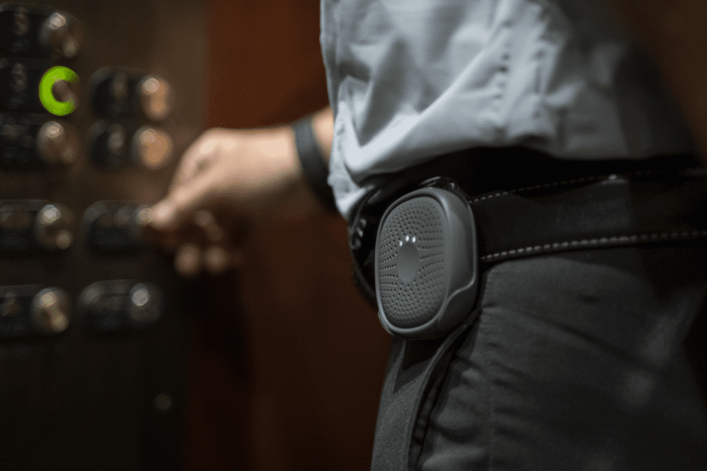 An employee wearing Relay, pushing an elevator button.