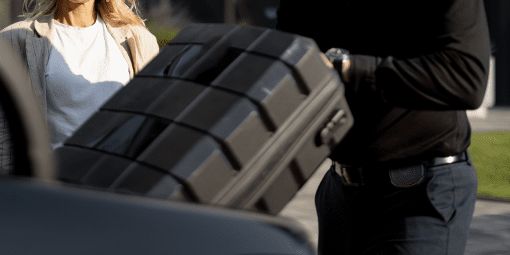 A valet worker wearing Relay helping a guest unload luggage from their car.