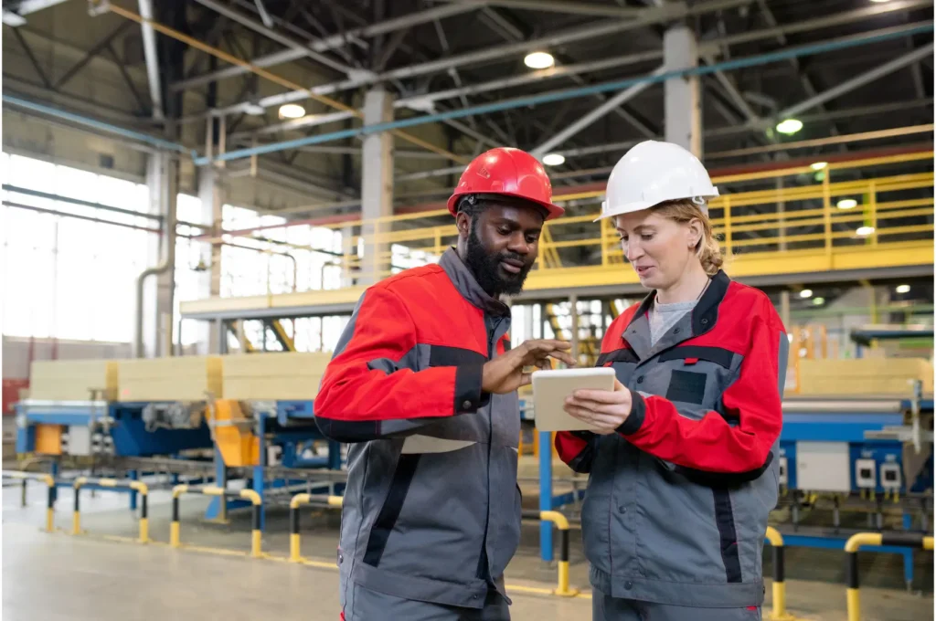 Manufacturing workers in red hats and jackets talking to about innovation on the shop floor