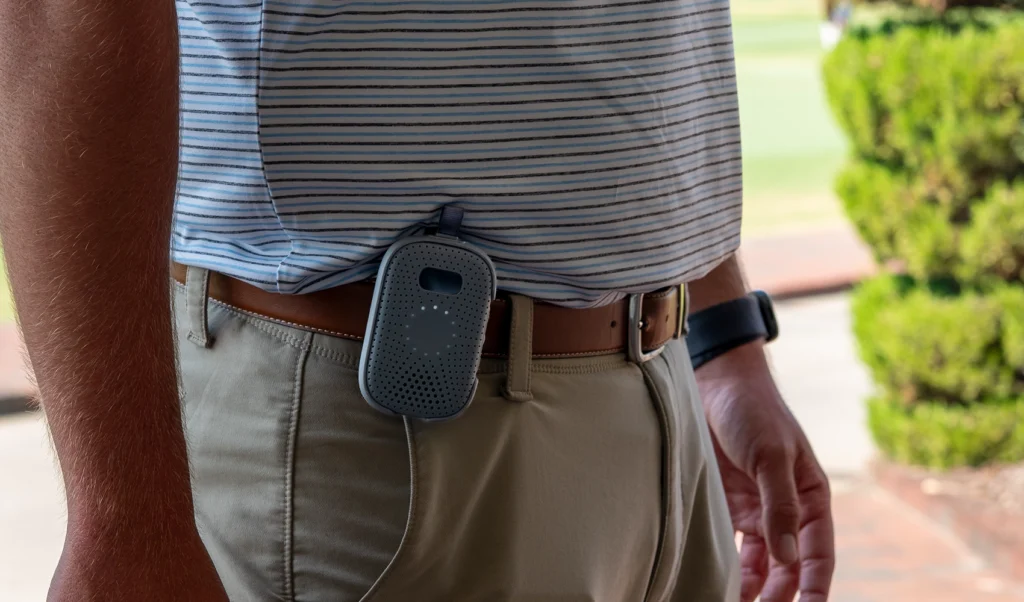 Relay device clipped to a worker’s belt while standing near the golf course.