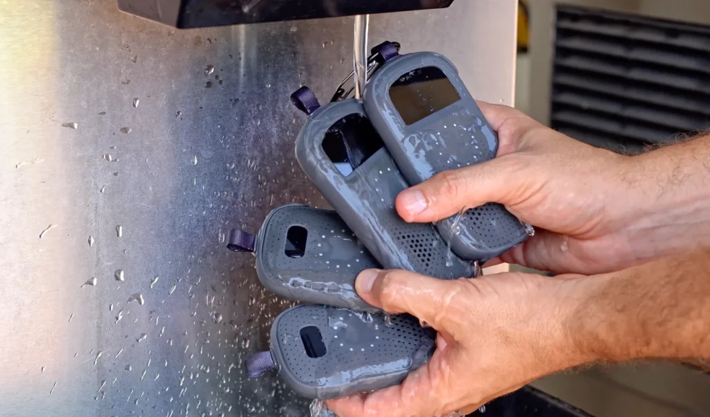 Close-up of a person holding multiple Relay devices under running water, demonstrating their waterproof durability.