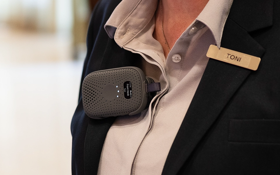 RelayM device clipped to a front desk staff member’s jacket for instant team communication.